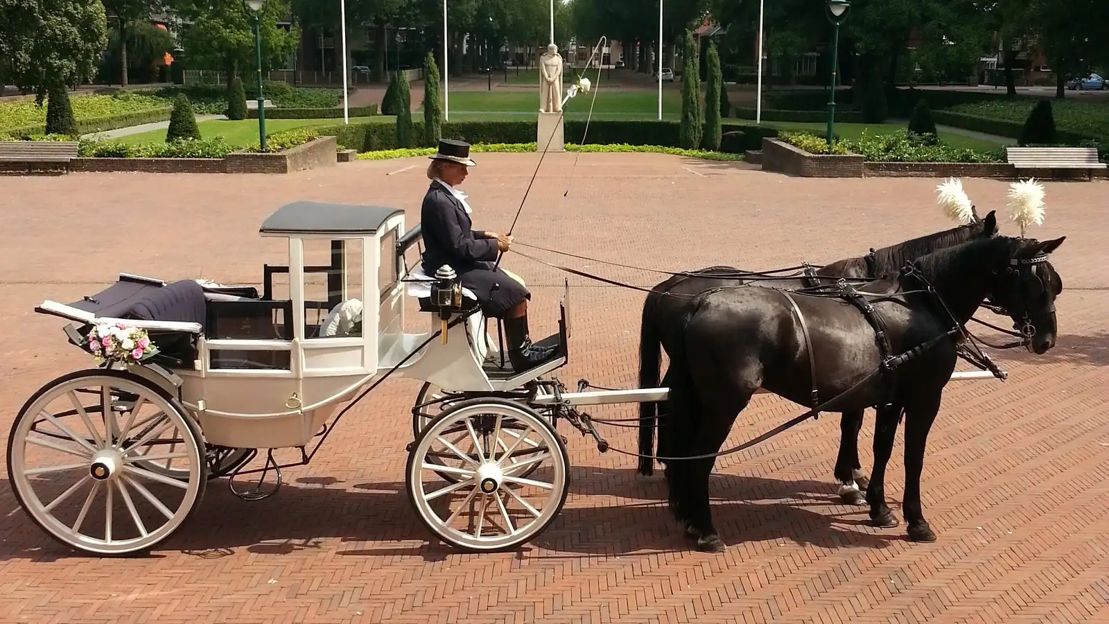Witte landaulet trouwkoets met koetsier op een plein