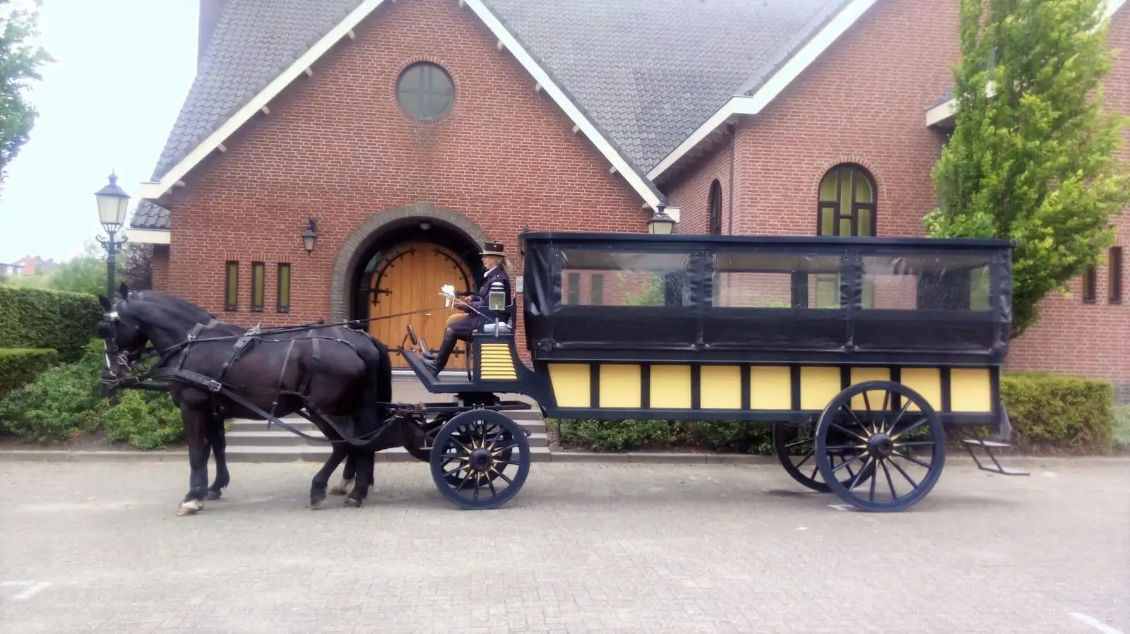 Janplezier met twee zwarte paarden voor een bakstenen boerderij